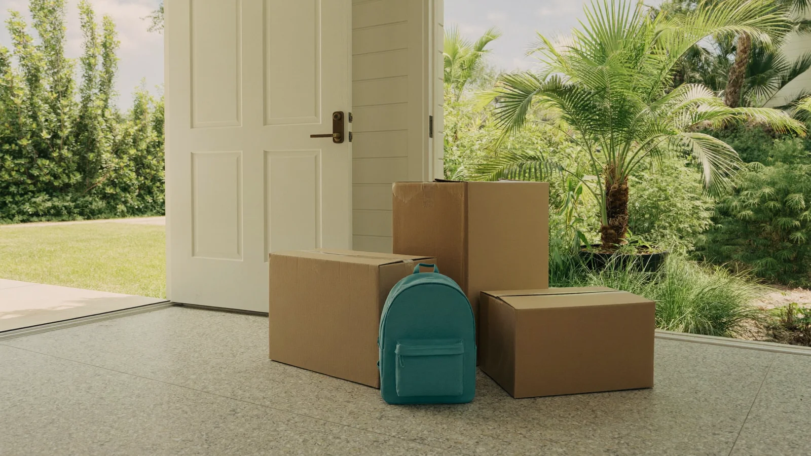 Moving boxes and a child's backpack by a front door before a family relocation in Palm Beach County